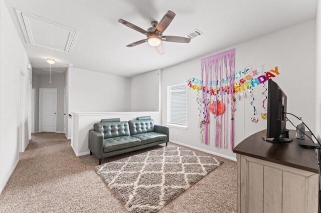 interior space with carpet floors, attic access, baseboards, and a ceiling fan