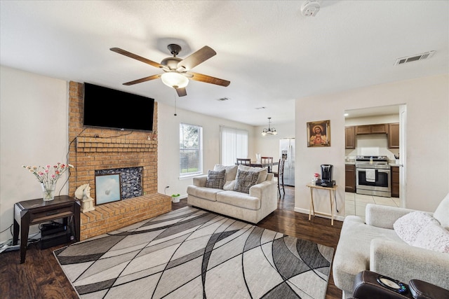 living room with a brick fireplace, ceiling fan, visible vents, and wood finished floors