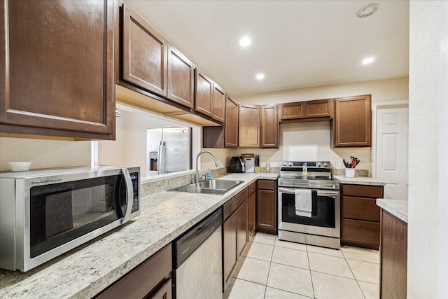 kitchen with light tile patterned floors, recessed lighting, light countertops, appliances with stainless steel finishes, and a sink