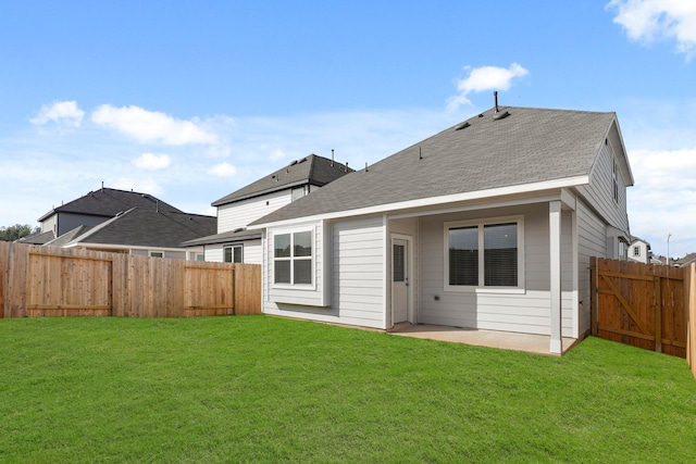 back of house with a shingled roof, a patio area, a fenced backyard, and a yard