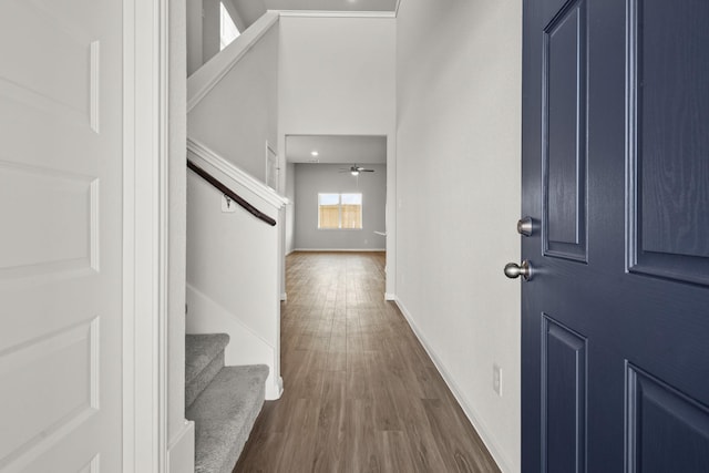 foyer entrance featuring dark wood-style floors, a towering ceiling, ceiling fan, baseboards, and stairs