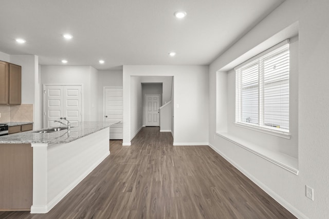 interior space featuring recessed lighting, dark wood-type flooring, a sink, light stone countertops, and baseboards