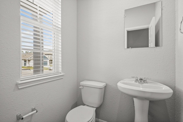 half bathroom featuring a textured wall and toilet