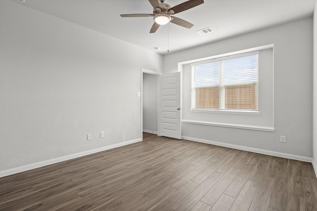 unfurnished room with baseboards, visible vents, ceiling fan, and wood finished floors