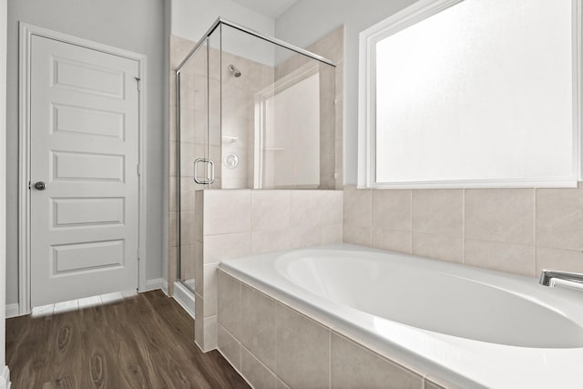 bathroom with a garden tub, a shower stall, and wood finished floors