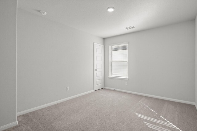 carpeted spare room with visible vents and baseboards