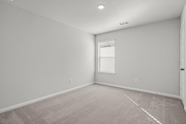 spare room featuring visible vents, light carpet, and baseboards