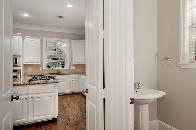 kitchen featuring stainless steel appliances, white cabinetry, tasteful backsplash, dark hardwood / wood-style flooring, and dark stone counters