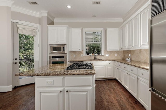 kitchen with stainless steel appliances, stone countertops, a center island, and sink