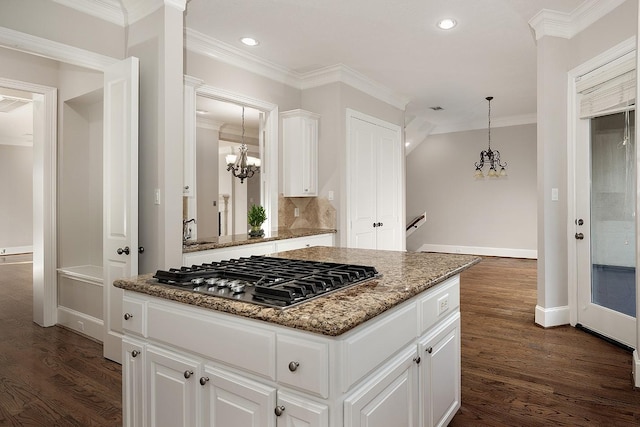 kitchen with white cabinetry, stainless steel gas stovetop, a kitchen island, and a notable chandelier