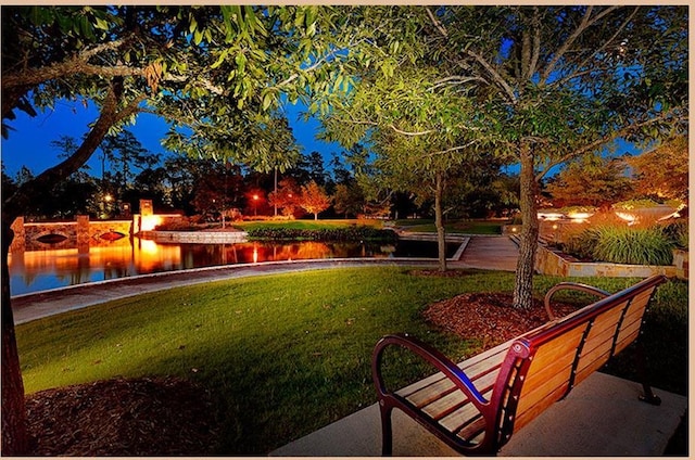 yard at night featuring a water view