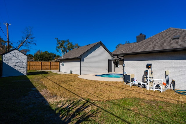 rear view of house featuring a storage unit, a fenced in pool, and a lawn