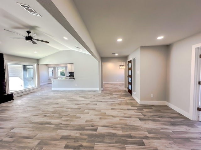 unfurnished living room featuring ceiling fan, vaulted ceiling, and light wood-type flooring