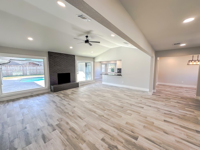 unfurnished living room with ceiling fan, lofted ceiling, a fireplace, and light hardwood / wood-style floors