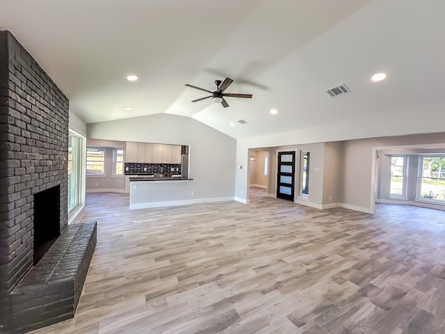 unfurnished living room with light hardwood / wood-style flooring, a fireplace, ceiling fan, and vaulted ceiling