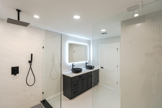 bathroom with a tile shower, vanity, and tile patterned floors