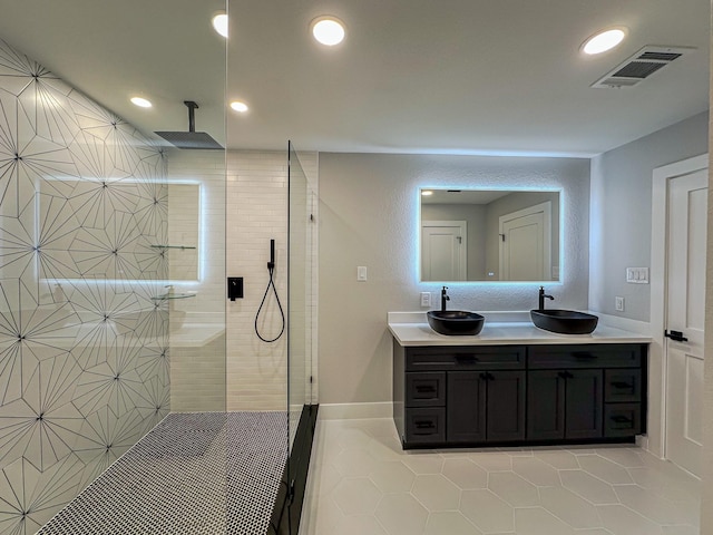 bathroom with a tile shower, vanity, and tile patterned flooring