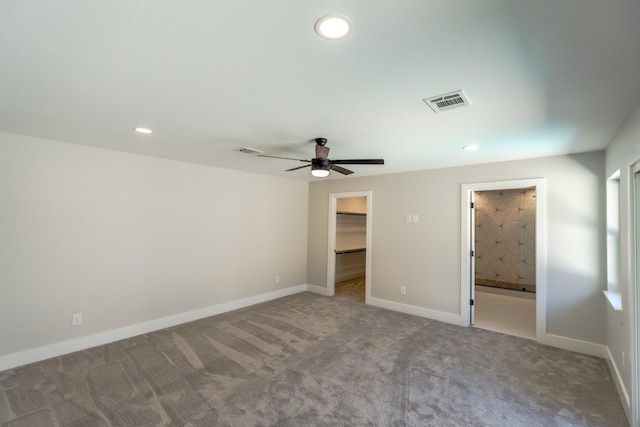 unfurnished bedroom featuring a walk in closet, light colored carpet, ensuite bath, and a closet