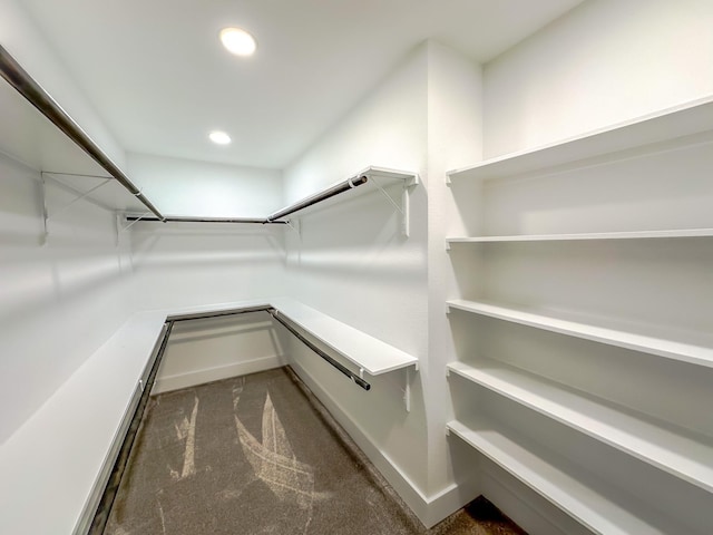 walk in closet featuring dark colored carpet