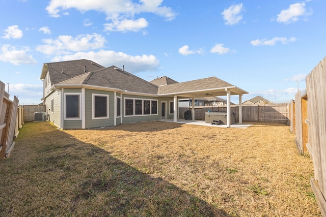 rear view of property with a yard, central AC, a patio area, and a hot tub