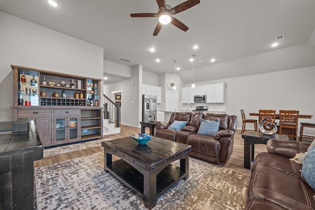 living room featuring ceiling fan, sink, and light wood-type flooring