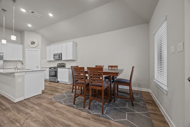 dining room with lofted ceiling, dark hardwood / wood-style floors, and sink