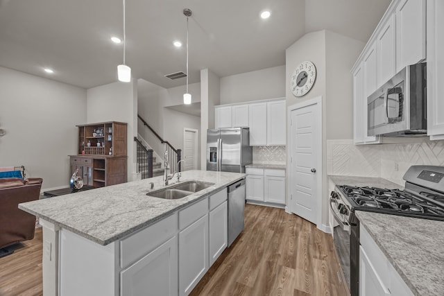 kitchen featuring stainless steel appliances, a kitchen island with sink, sink, and white cabinets