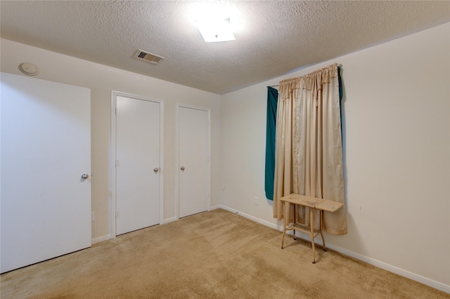 unfurnished bedroom with light colored carpet and a textured ceiling