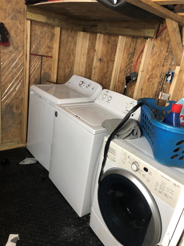 laundry area with wooden walls and washing machine and clothes dryer