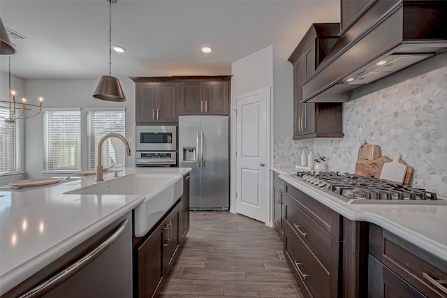 kitchen featuring pendant lighting, sink, custom exhaust hood, stainless steel appliances, and dark brown cabinets