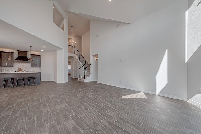 8934 Stanley Oak Dr, Missouri City, TX 77459 - unfurnished living room featuring high vaulted ceiling, baseboards, wood finished floors, stairs, and a chandelier