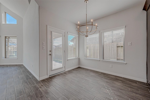 unfurnished dining area with dark wood-type flooring, an inviting chandelier, and a wealth of natural light