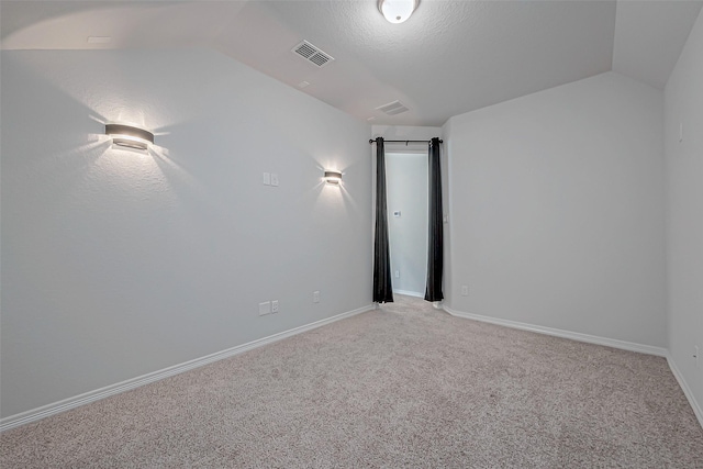 spare room featuring light carpet and vaulted ceiling