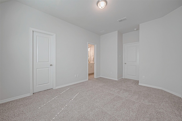 unfurnished bedroom with light carpet and connected bathroom