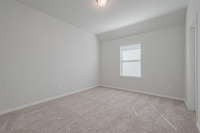 carpeted empty room featuring vaulted ceiling