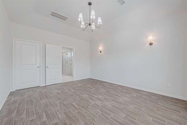 unfurnished room with a chandelier and light hardwood / wood-style flooring