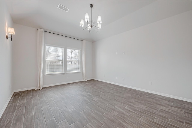 empty room with a notable chandelier and light hardwood / wood-style flooring