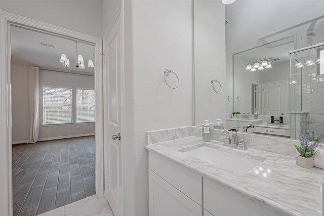 bathroom with a shower with door, vanity, and a notable chandelier