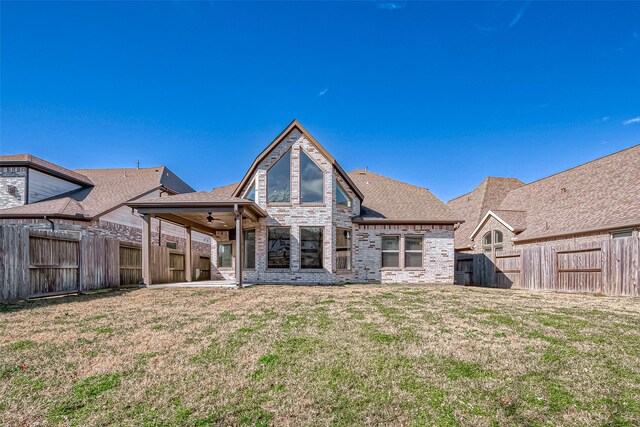 rear view of property featuring a lawn and ceiling fan