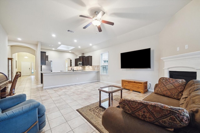 tiled living room featuring ceiling fan and a skylight