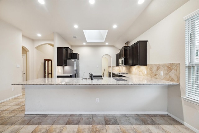 kitchen with stainless steel appliances, light stone countertops, and kitchen peninsula