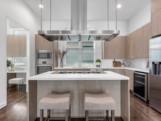 kitchen with wine cooler, a center island, appliances with stainless steel finishes, and island exhaust hood