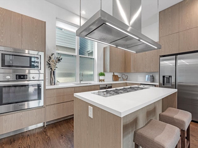 kitchen featuring sink, stainless steel appliances, island exhaust hood, a kitchen island, and dark hardwood / wood-style flooring