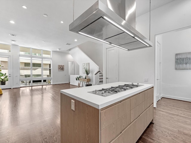 kitchen featuring gas stovetop, island exhaust hood, hardwood / wood-style flooring, and a center island