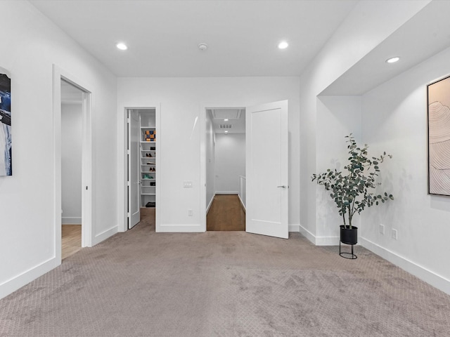 unfurnished bedroom with light carpet and a spacious closet