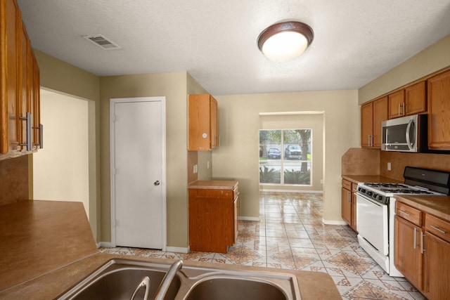 kitchen with white range with gas stovetop and a textured ceiling