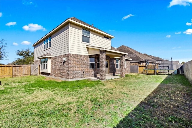 rear view of property featuring a trampoline, a yard, and a patio area