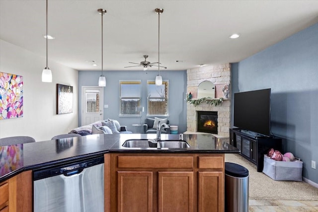 kitchen featuring a fireplace, decorative light fixtures, dishwasher, sink, and light carpet