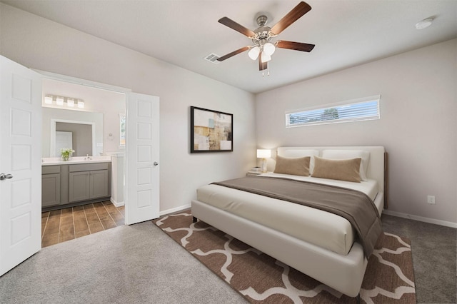 carpeted bedroom with sink, ensuite bath, and ceiling fan