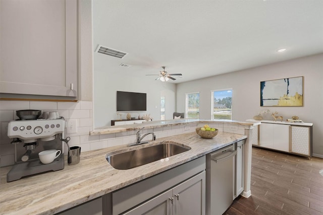 kitchen featuring dark hardwood / wood-style flooring, sink, light stone counters, and decorative backsplash